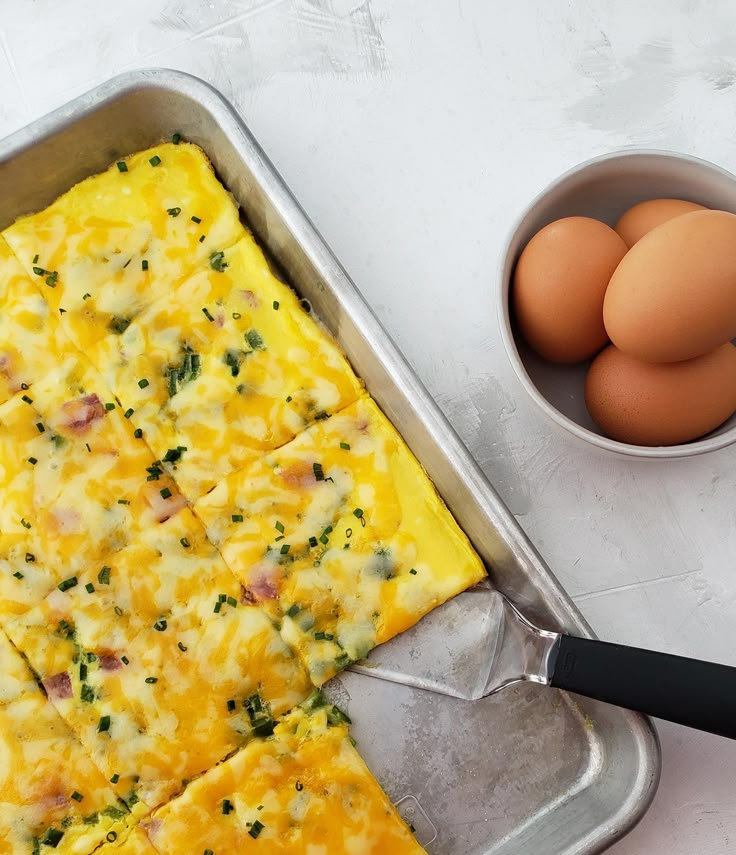 an egg and cheese casserole in a pan next to eggs