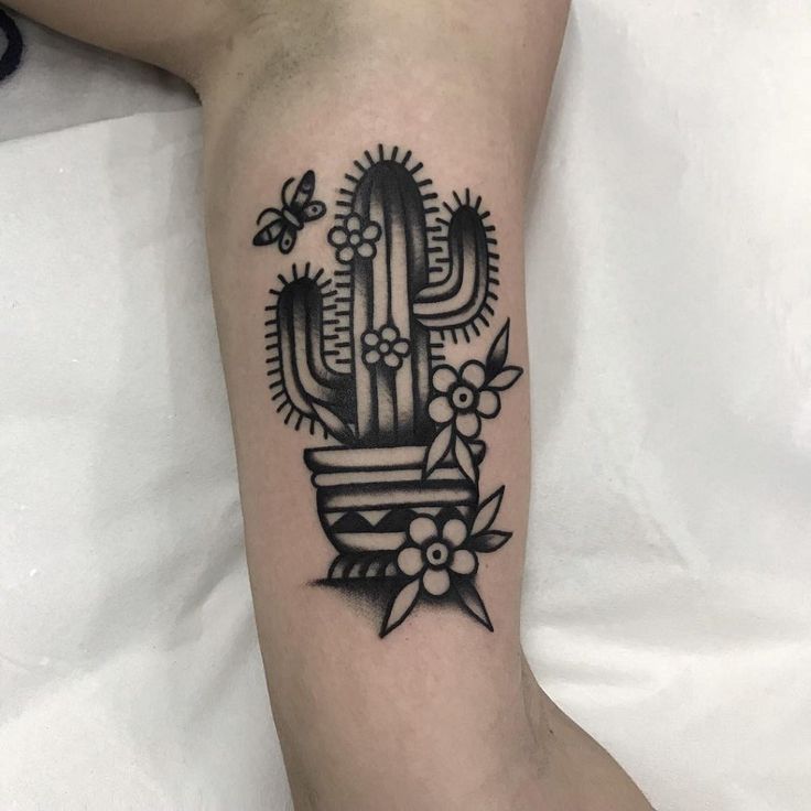 a black and white photo of a cactus tattoo on the left leg with flowers around it