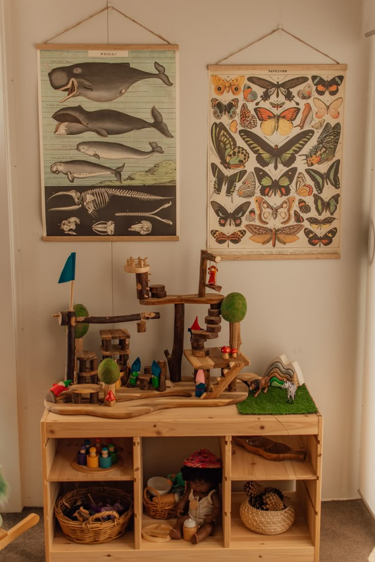 there is a wooden shelf with toys on it in the room next to two paintings