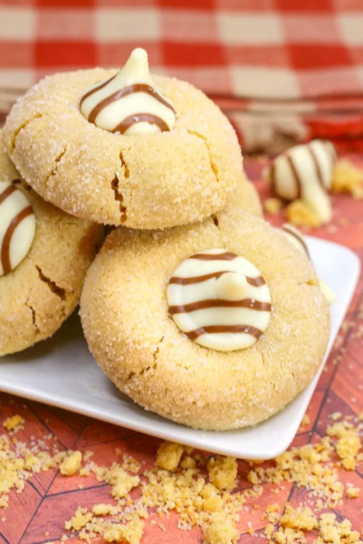 three cookies with white frosting and chocolate drizzled on them sitting on a plate