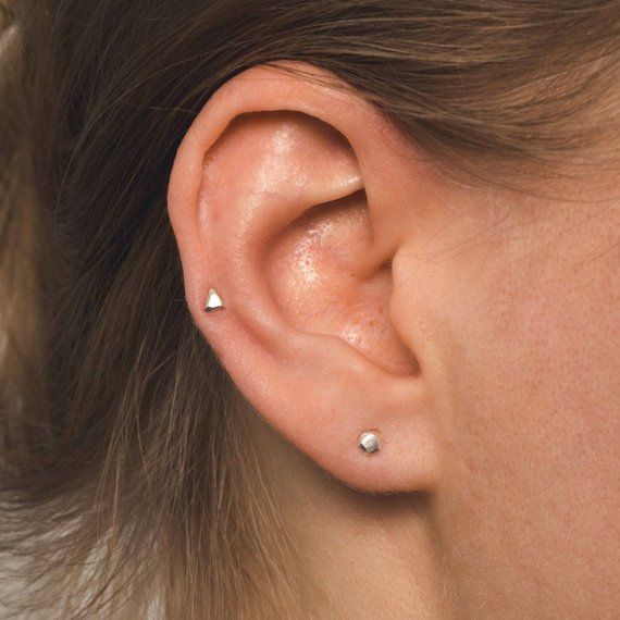 a close up of a person's ear with two small piercings on it