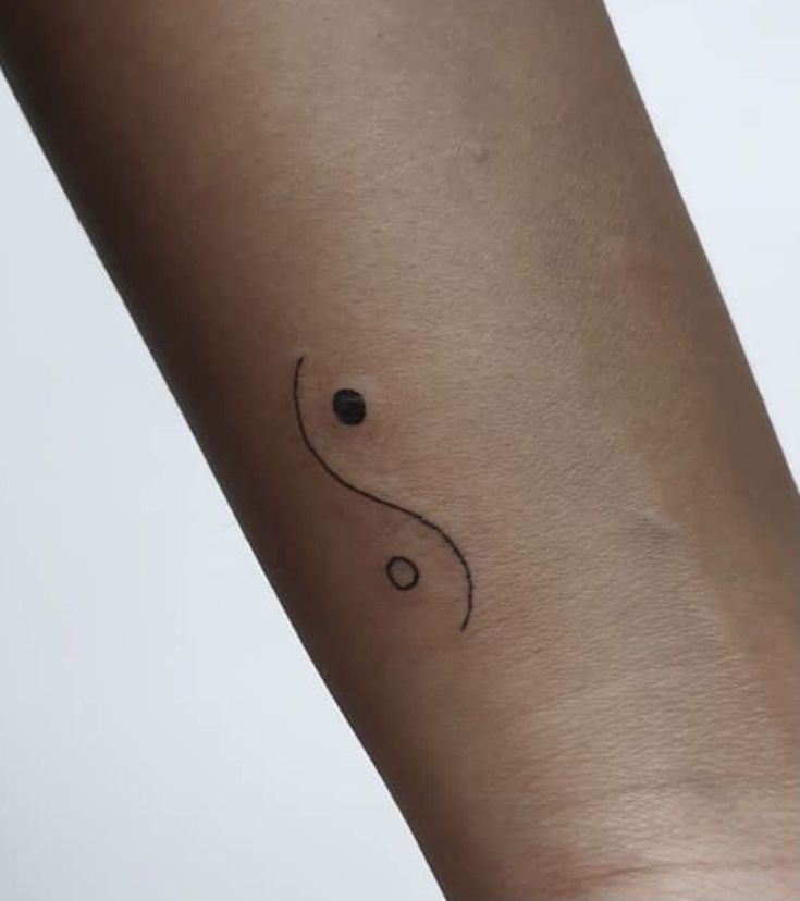 a woman's arm with a small black dot tattoo on the left side of her arm