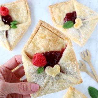 small pastries with raspberries and bananas on them are being held by someone's hand