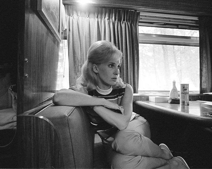 black and white photograph of a woman sitting on a train seat looking out the window