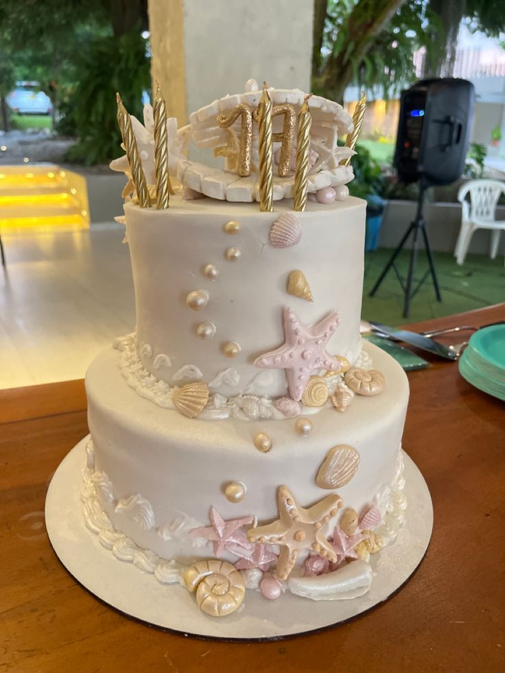 a three tiered wedding cake with seashells and starfish