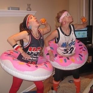 two girls in costumes are eating donuts and drinking orange juice