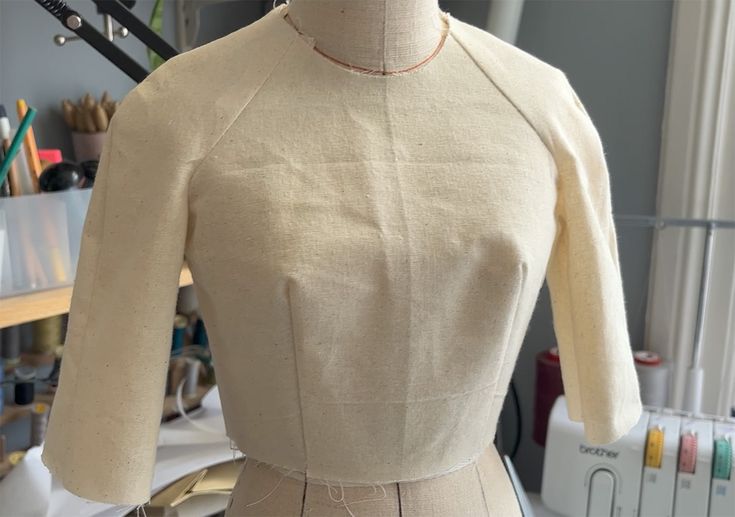 a dressmaker's mannequin in front of a sewing machine