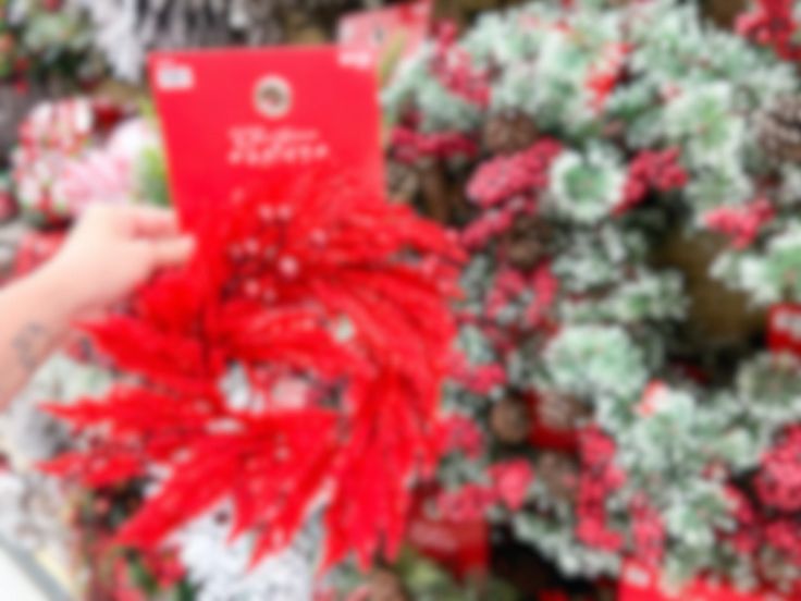 a person is holding up a red card in front of christmas tree decorations at a store