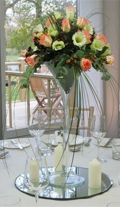 a vase filled with lots of flowers on top of a table next to wine glasses