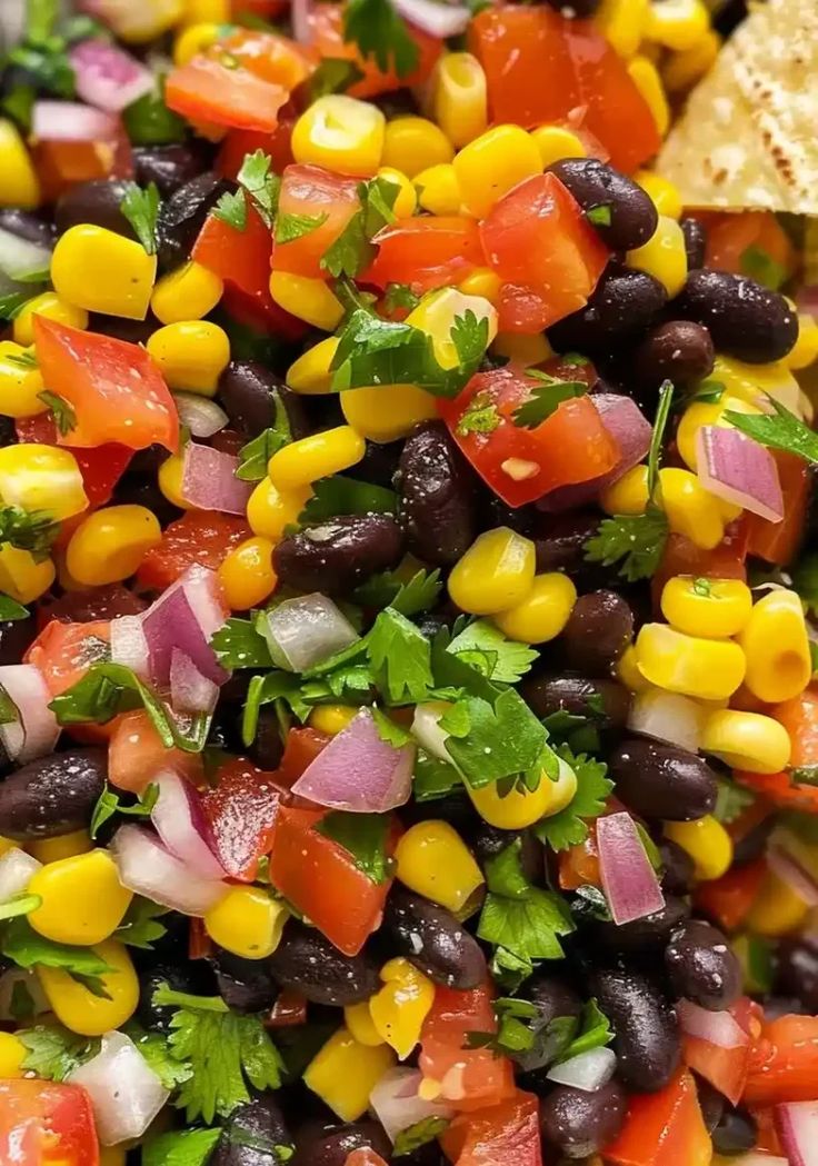 a salad with black beans, corn, tomatoes and cilantro on top is shown