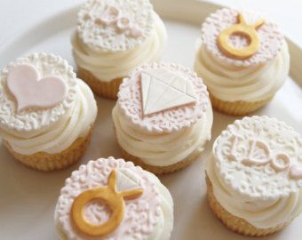 six decorated cupcakes on a plate with white frosting and gold trimming