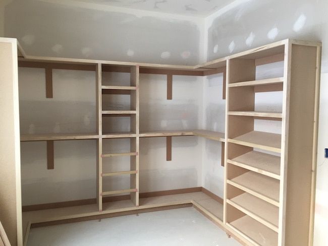 an empty walk in closet with wooden shelves