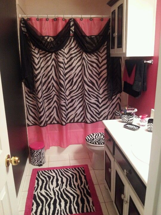 a zebra print shower curtain in a bathroom with pink and black accessories on the floor