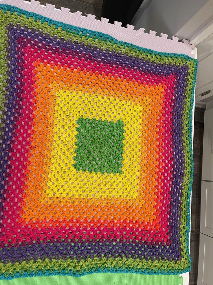 a multicolored crocheted blanket hanging from the ceiling