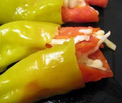 several peppers are stuffed with cheese and tomato on a black plate, ready to be eaten