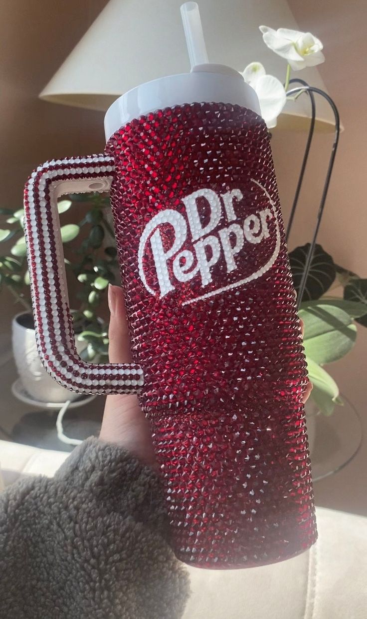 a person holding up a red and white cup with the word dr pepper on it