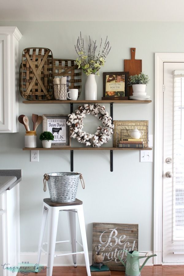 some shelves that have baskets and wreaths on top of them in a room with wood floors