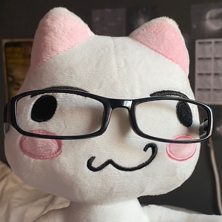 a white stuffed cat with glasses on it's face