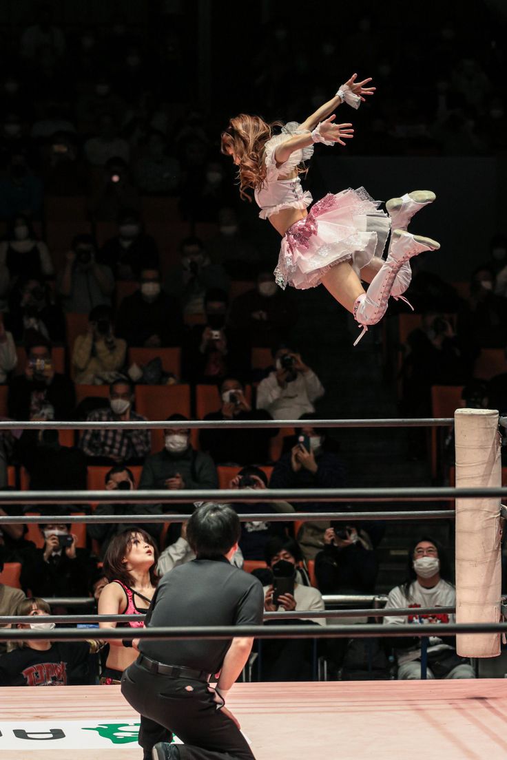 a woman in a pink dress is doing tricks on a skateboard while people watch