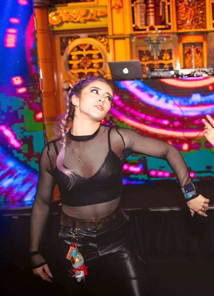 a woman standing in front of a laptop computer on top of a stage with lights behind her