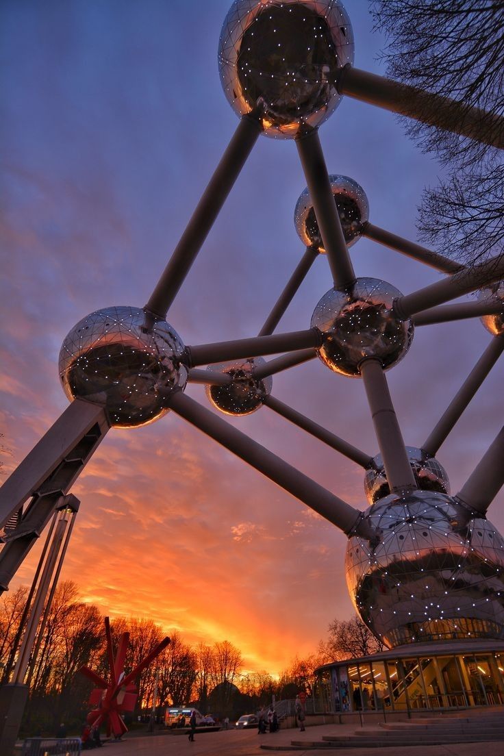 the sun is setting behind an artistic structure with mirrored balls on it's sides