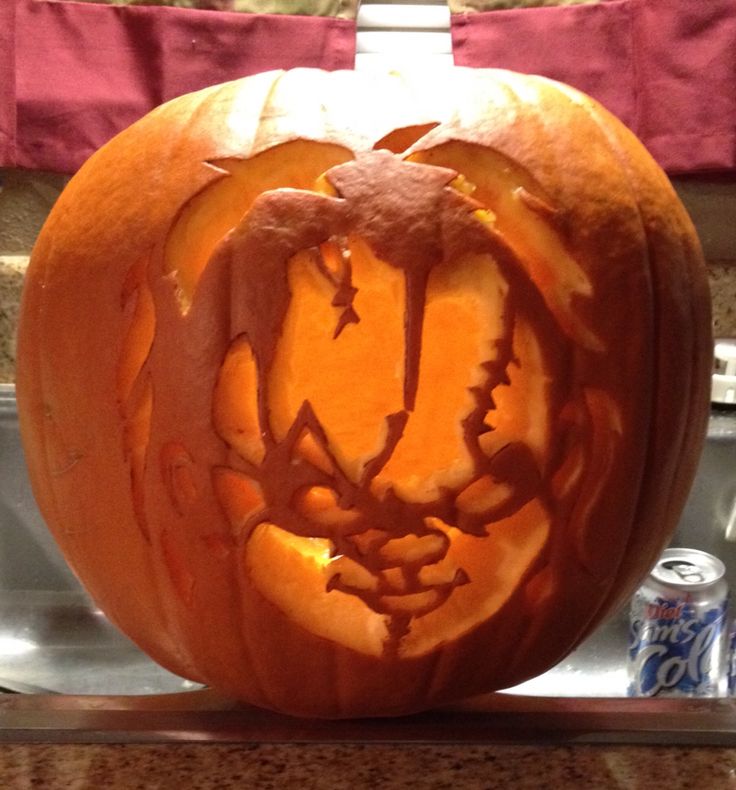 a carved pumpkin sitting on top of a kitchen counter next to a can of soda