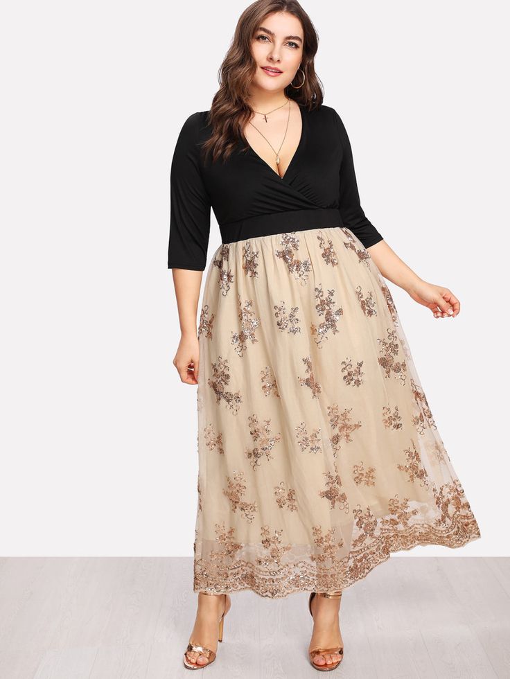 a woman in a black top and tan floral print skirt standing on a wooden floor