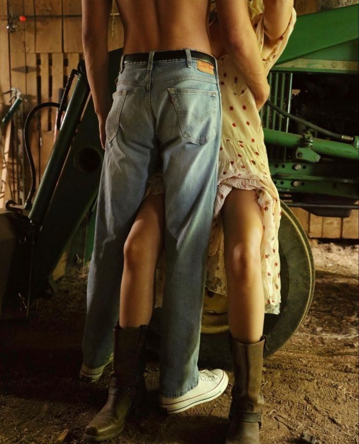 a man and woman standing next to each other in front of a farm equipment shed