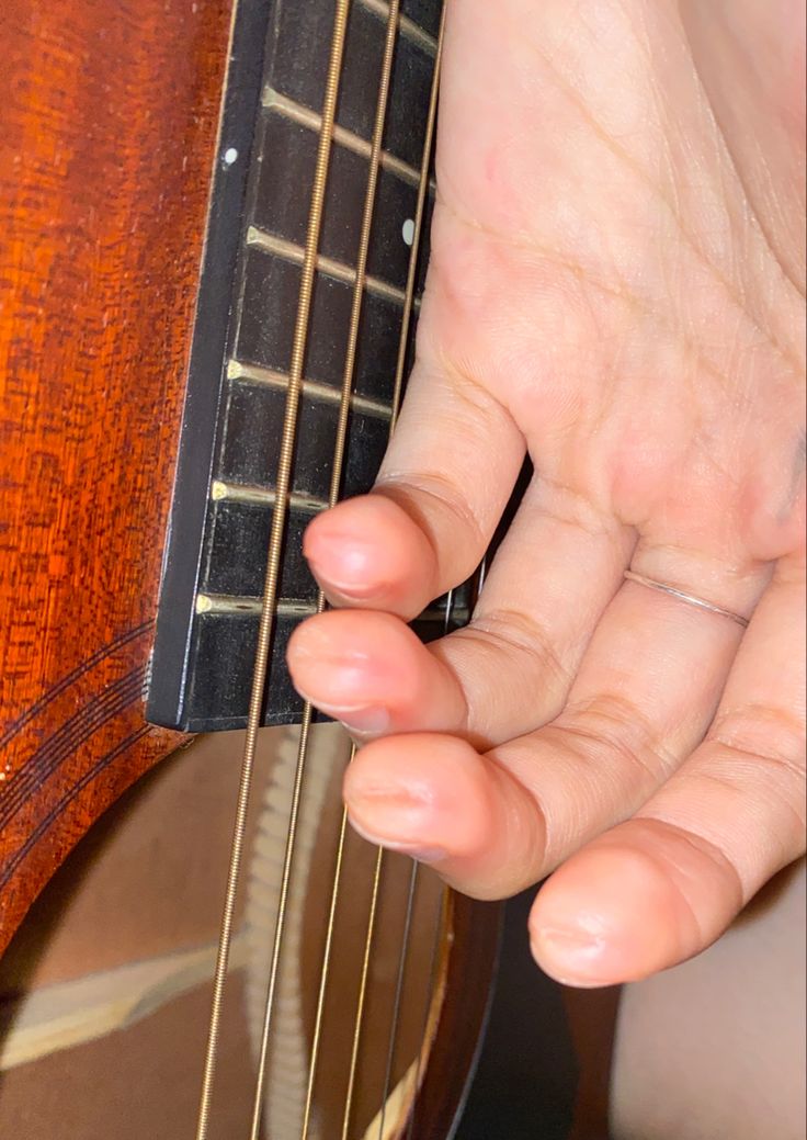 a close up of a person's hand holding an acoustic guitar