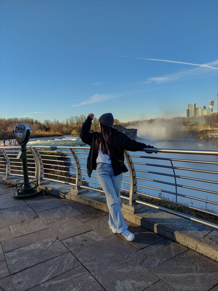 a woman standing on the edge of a bridge with her arms in the air