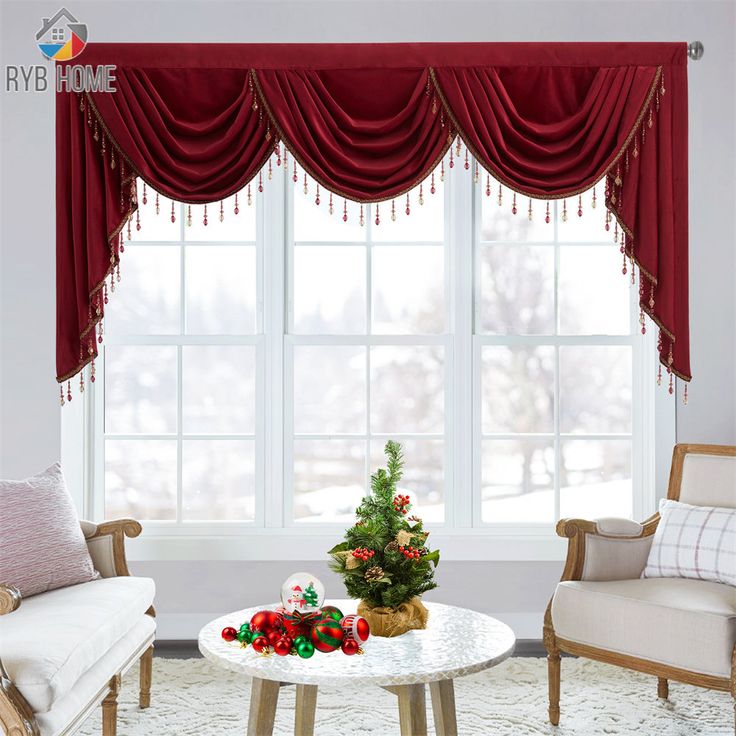 two chairs and a table in front of a window with red curtains on the windowsill