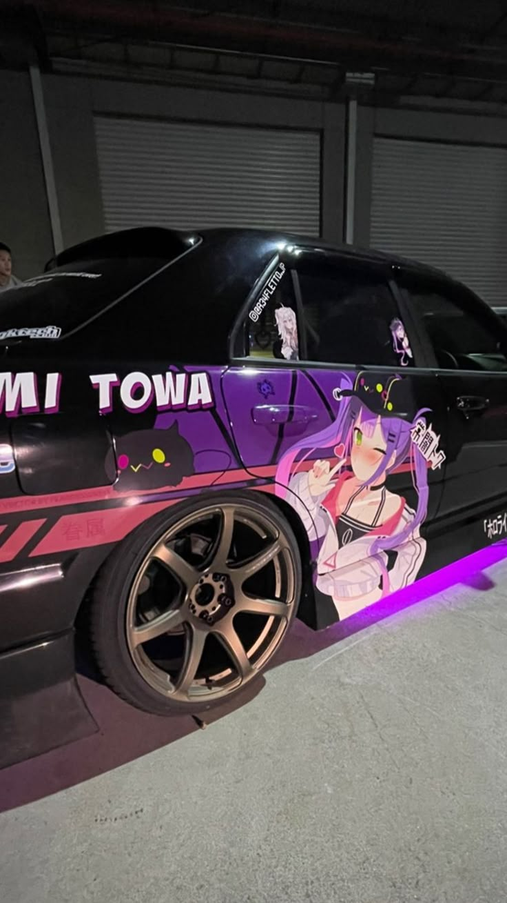 a car that has been painted with anime characters on the side and is parked in a garage