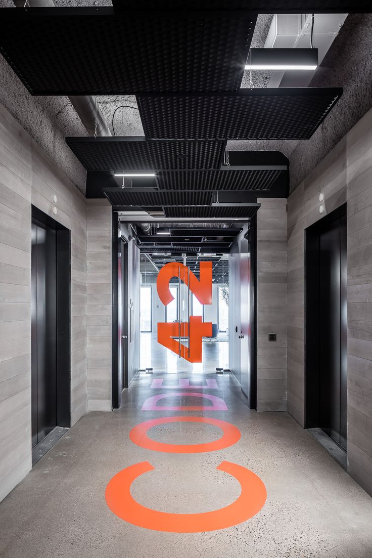 an orange and white sign is in the middle of a long hallway with black doors