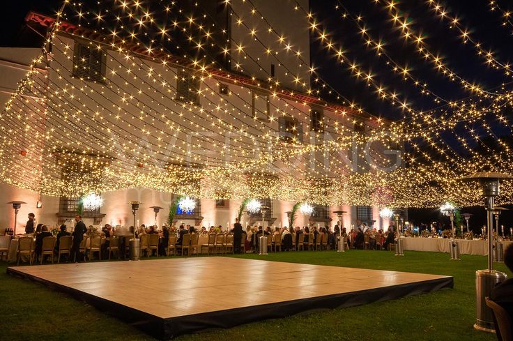 a large dance floor in front of a building with lots of lights strung over it