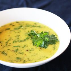 a white bowl filled with broccoli soup on top of a blue table cloth