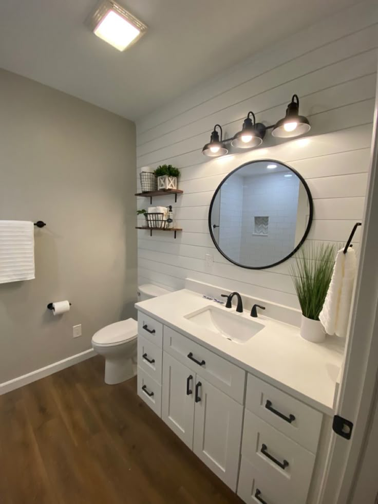 a bathroom with white cabinets and wood floors