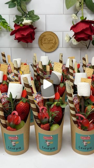 strawberries, apples and marshmallows are arranged in buckets