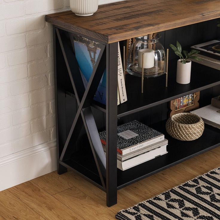 a book shelf with books on it next to a rug and potted plant in the corner