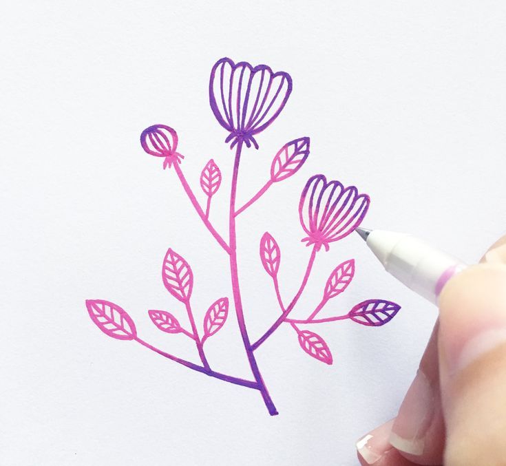 someone is drawing flowers on paper with a marker