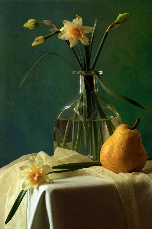 a vase with flowers and a pear on a table