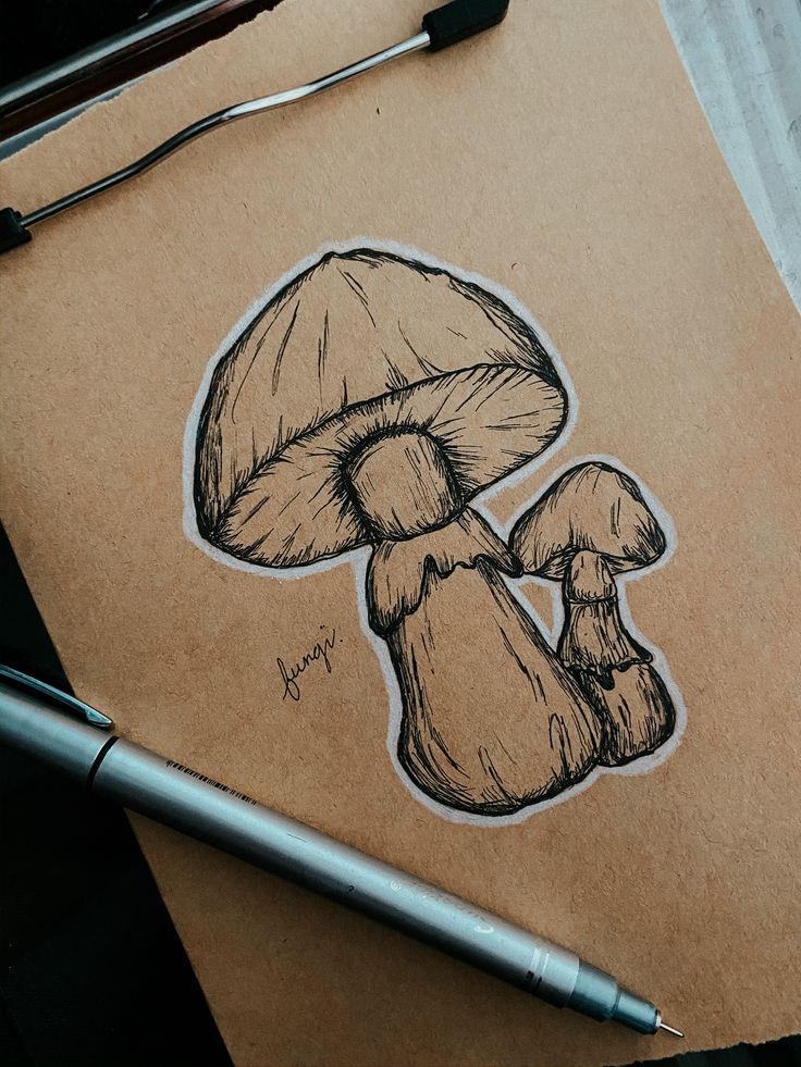 a drawing of a mushroom sitting on top of a piece of paper next to a pen