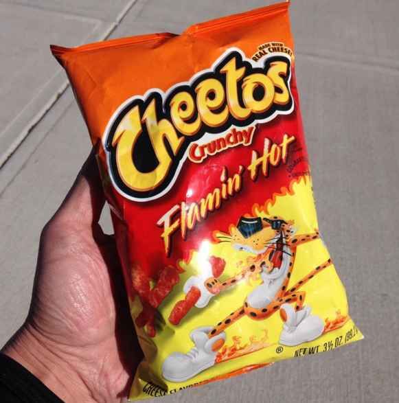 a hand holding a bag of cheetos candy