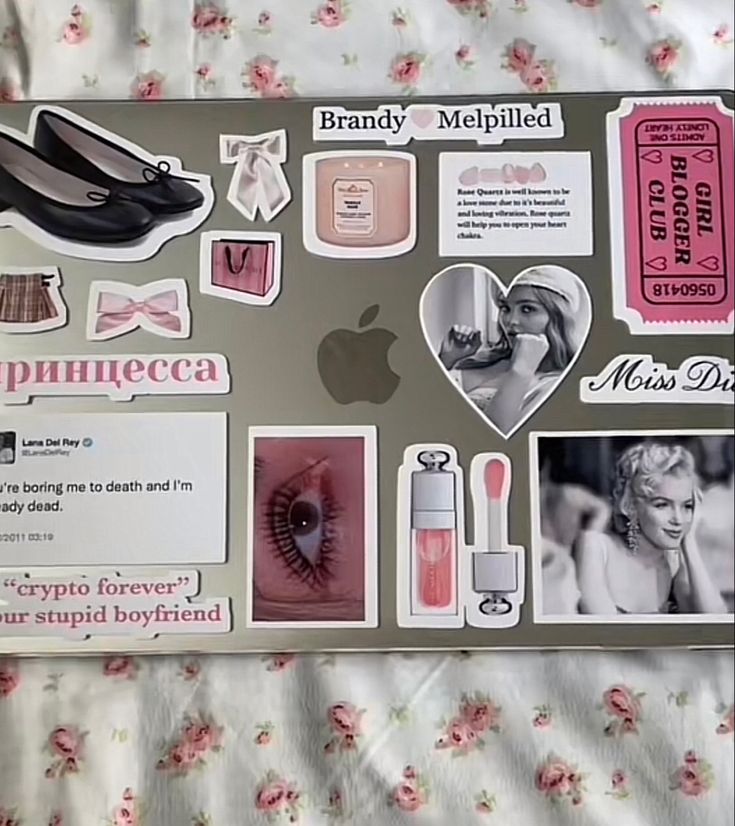 an open laptop computer sitting on top of a bed covered in pink and white stickers