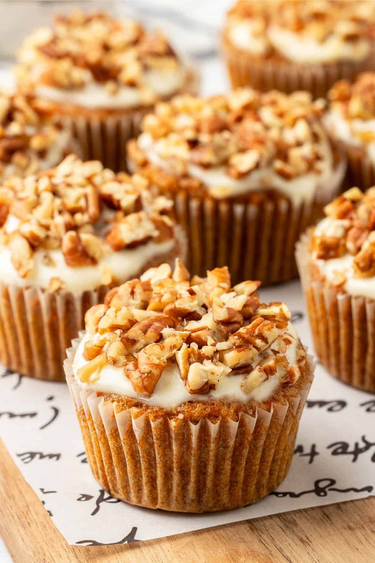 several cupcakes with white frosting and nuts on top are sitting on a piece of paper