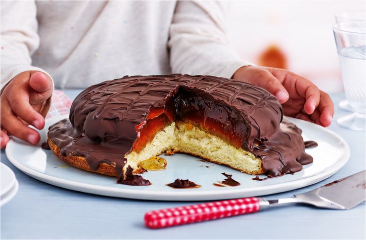 a chocolate covered bundt cake on a white plate with one slice missing from it