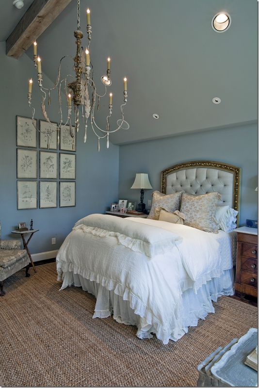 a bed room with a neatly made bed and a chandelier hanging from the ceiling