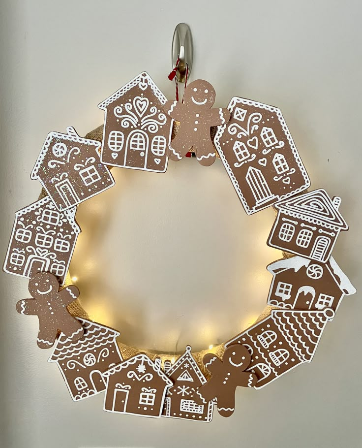 a christmas wreath with gingerbread cut out of it and lights on the front side