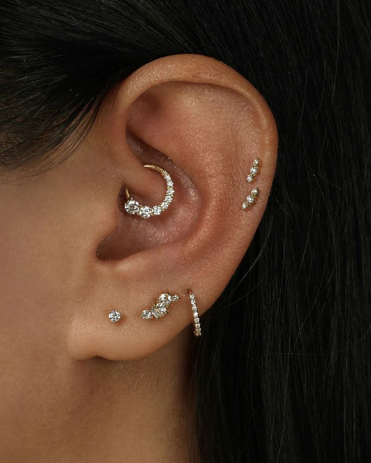 a woman's ear with three different piercings on her left side and one in the middle