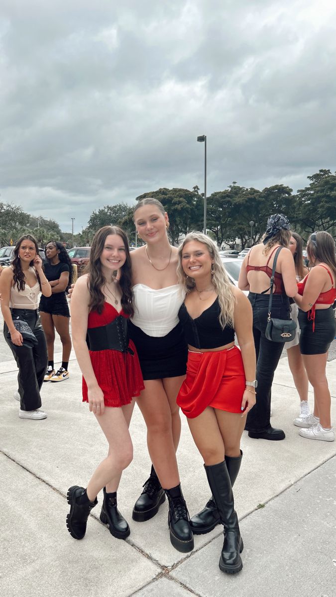 three girls posing for the camera in front of some other women wearing short skirts and high heels