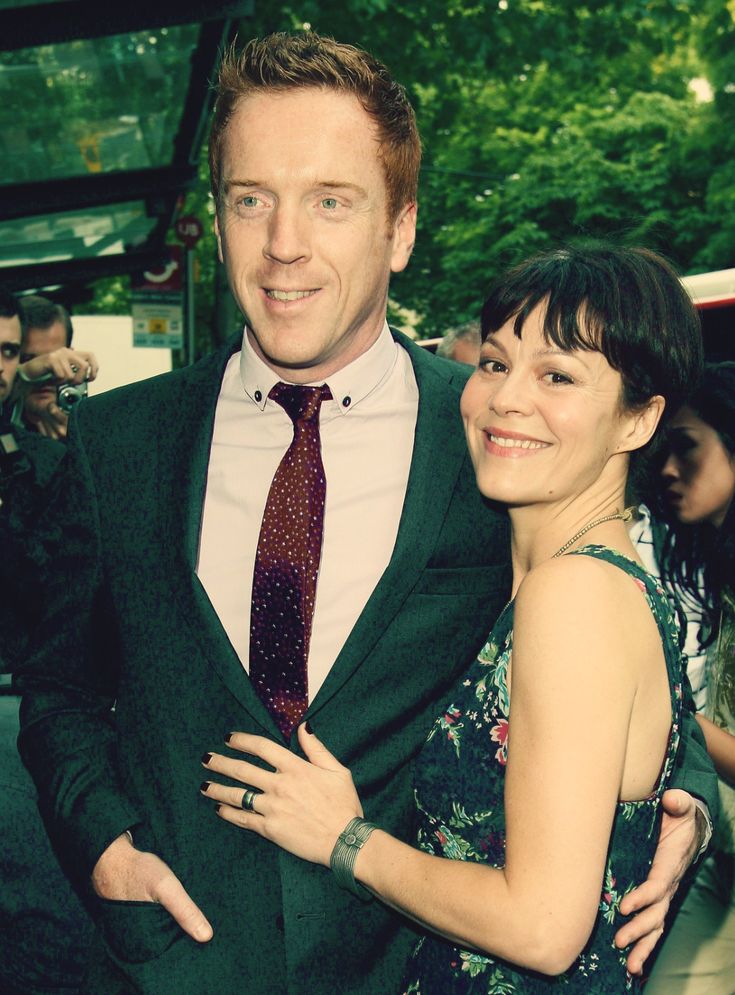 a man in a suit and tie standing next to a woman wearing a floral dress